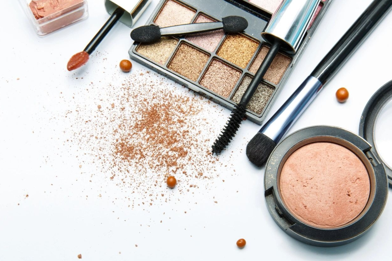 A table topped with makeup and brushes next to some other items.