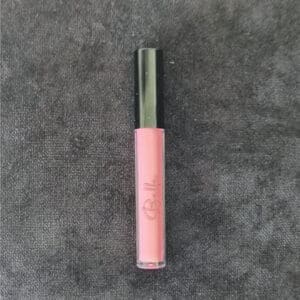 A pink lip gloss on top of a gray surface.