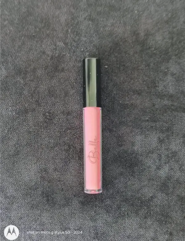 A pink lip gloss on top of a gray surface.