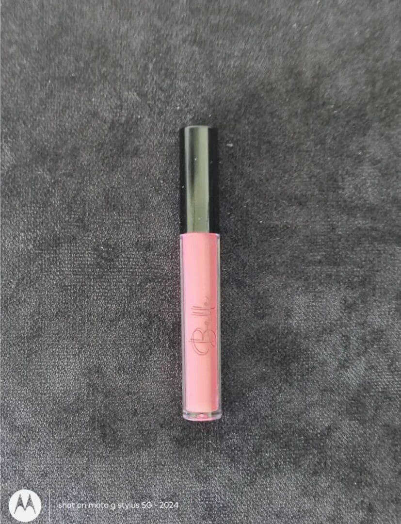 A pink lip gloss on top of a gray surface.