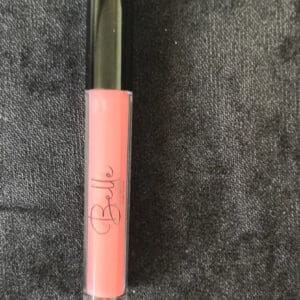 A pink lip gloss sitting on top of a gray surface.